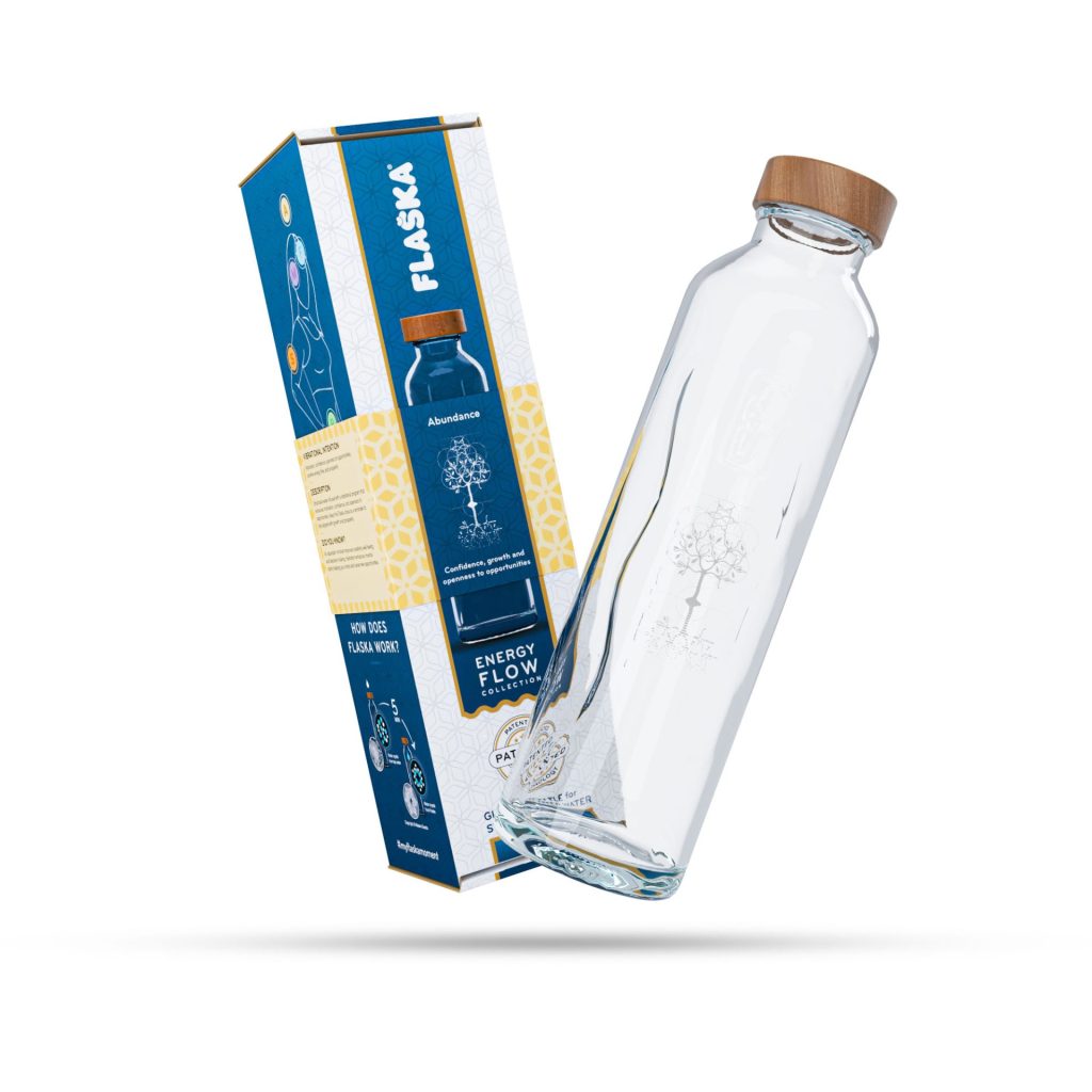 La botella Flaska Abundance de cristal con tapón de madera, flotando en el aire junto a su caja de embalaje.
