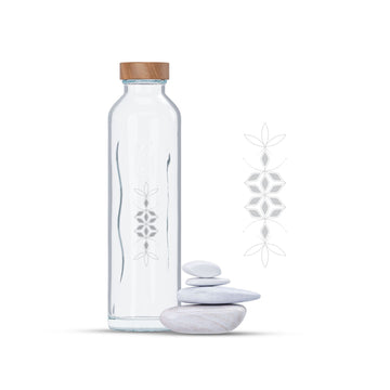 Botella de cristal con tapón de madera y un símbolo del cosmograma Flaska balance. A su lado, piedras apiladas y el símbolo ampliado.