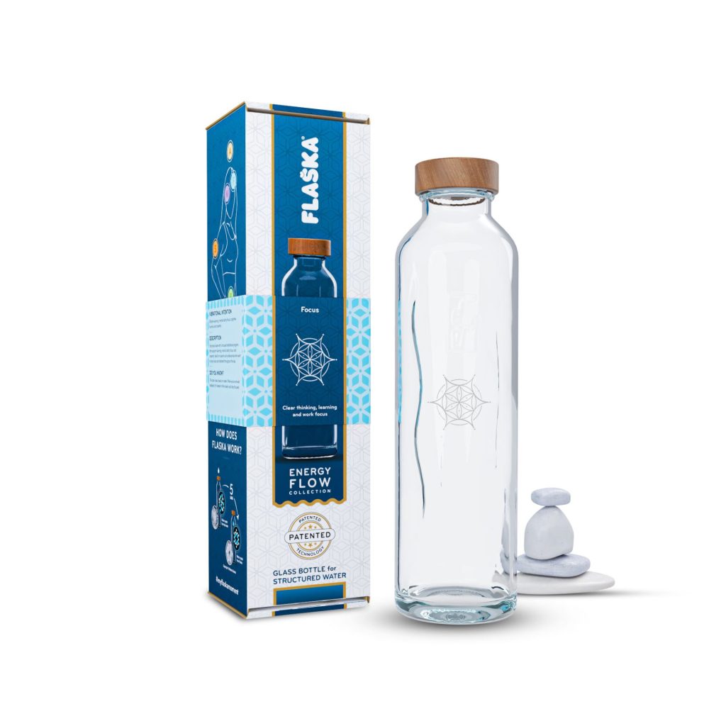 Botella de cristal flaska focus junto a su caja informativa y piedras blancas apiladas.
