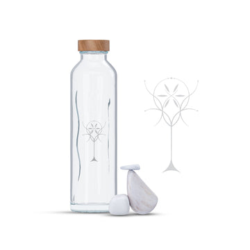 Botella de cristal con tapón de madera y símbolo grabado junto a piedras blancas decorativas.