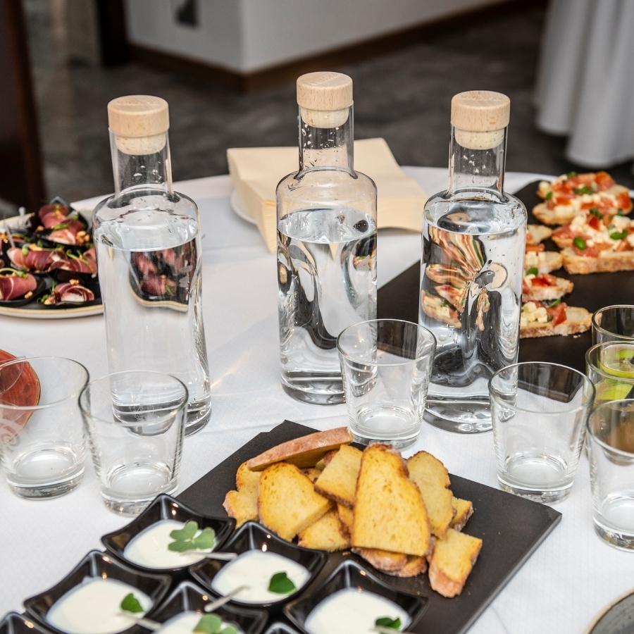jarras flaska 1l vodan y vasos de cristal para agua flaska junto a comida en mesa de coffee break